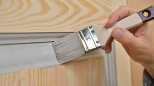 an unfinished wooden door being painted using a paintbrush