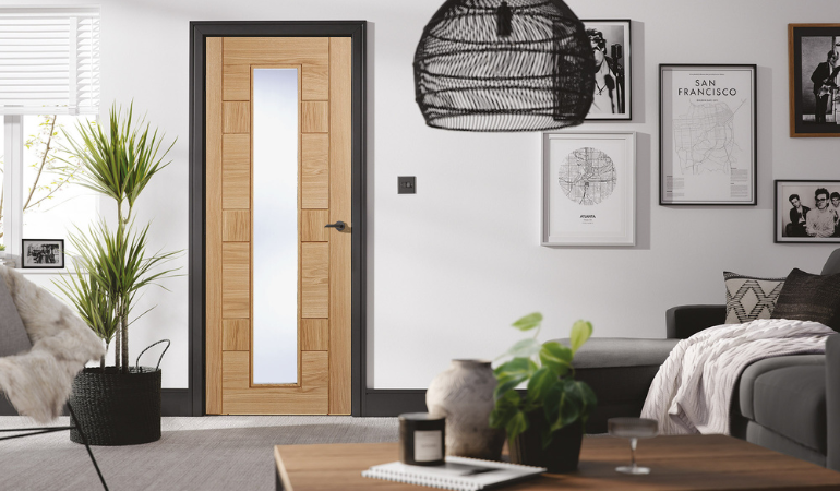 The Oak Corisca fire door which is an internal door with a light oak finish, 7 horizontal wooden panels and a vertical glass pane 